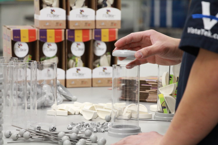 VistaTek employee assembling components with product boxes in the background.