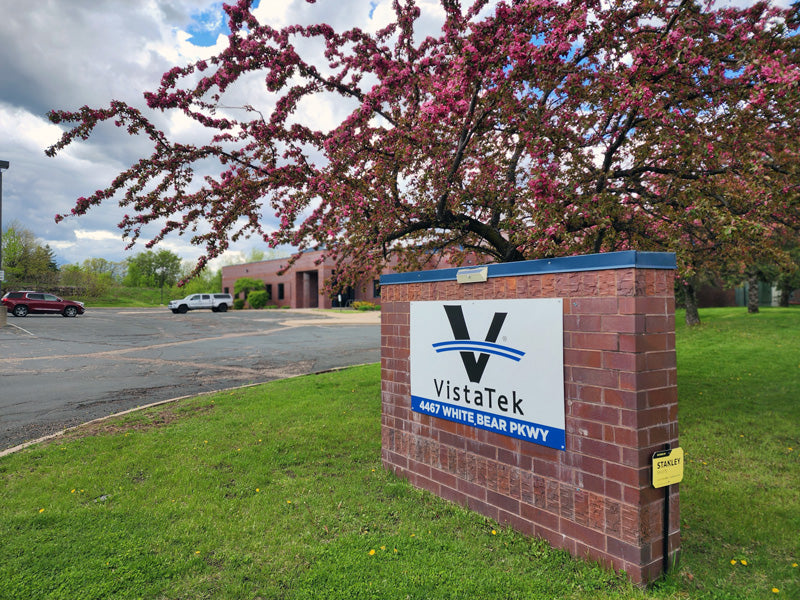 VistaTek sign and building entrance with blooming tree in the foreground.