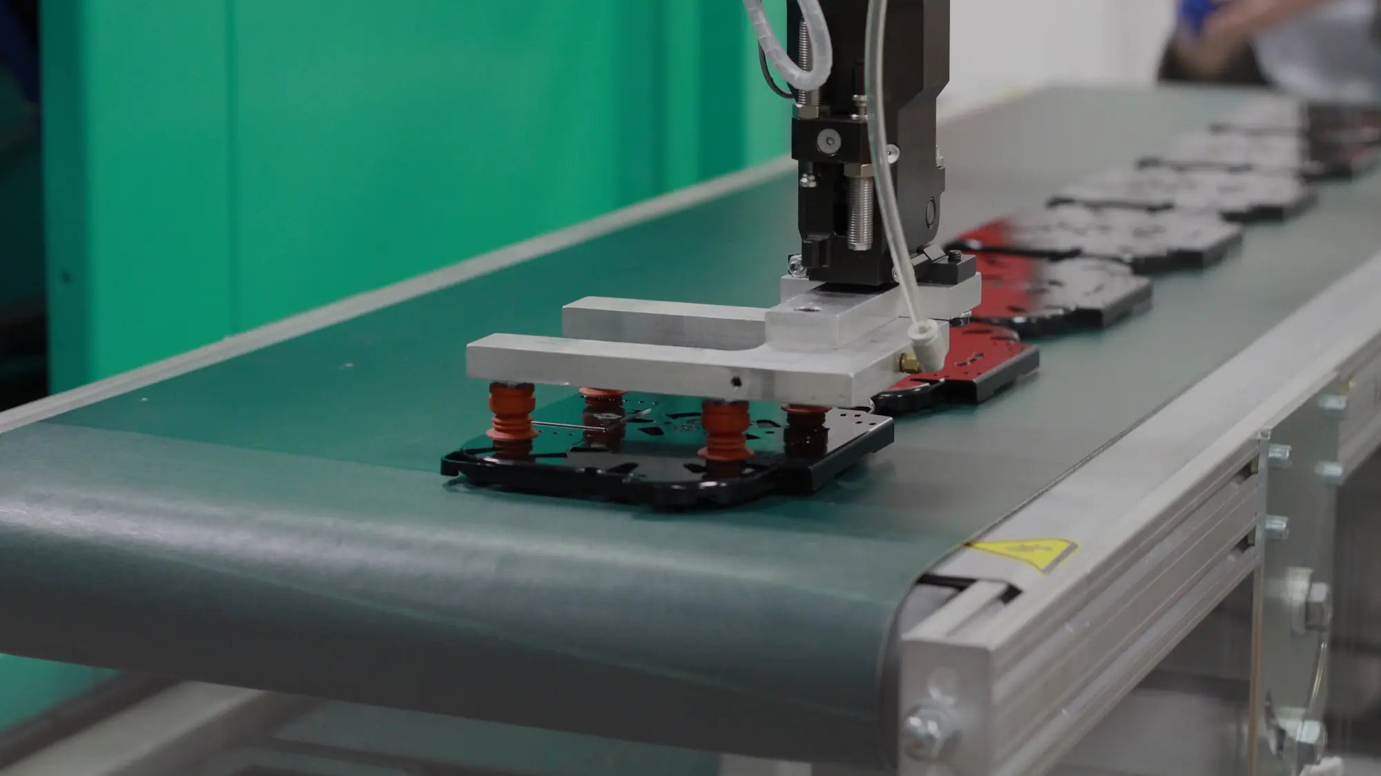 Automated injection molding robot handling parts on a conveyor belt.